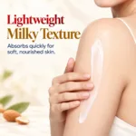 Woman applying Hi-Fi Honey & Almond Body Lotion to her shoulder, showing its lightweight milky texture against a dark brown background.